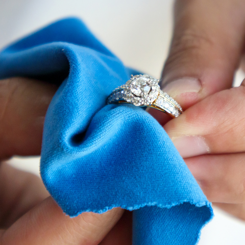 hands holding a ring and polishing with a blue sunshine cloth