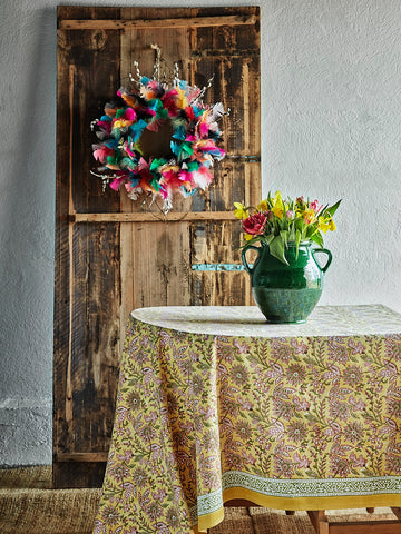 Table with a yellow tablecloth on and feather decorations in the background.