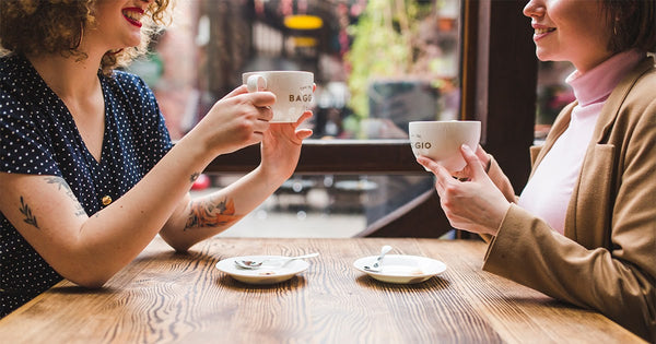 Duas amigas em um restaurante conversando tudo sobre café enquanto tomam a bebida.