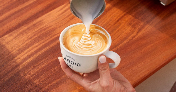 Pessoa fazendo latte art em uma xícara de café Baggio.