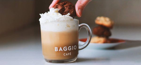 Xícara de cappuccino Baggio com alguns cookies empilhados ao fundo.