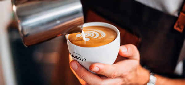 Pessoa fazendo uma latte art em formato de corações em um cappuccino Baggio.