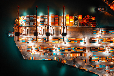 A cargo ship unloading containers at night