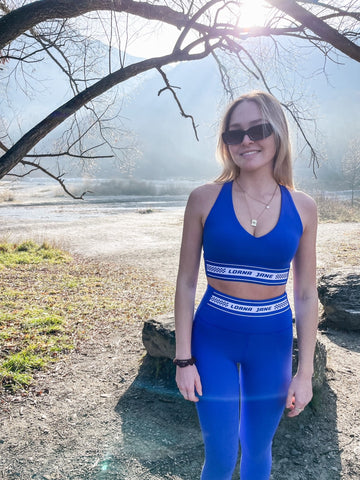 Sofia in front of the Arrow river in Arrowtown NZ, wearing the new season Qualify No Chafe Full Length Legging and Qualify Longline Sports Bra in Magnetic Blue by Lorna Jane