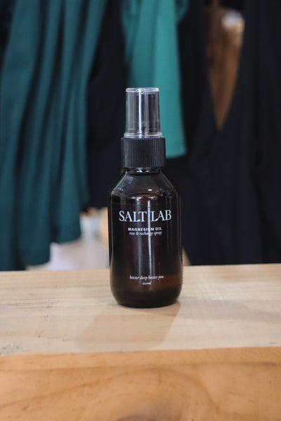 Salt Lab's original Magnesium Oil Spray in front of green activewear