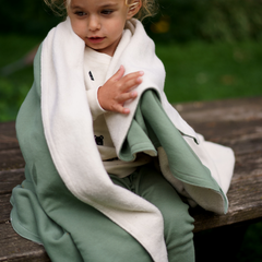 Toddler wrapped in moss green and natural cotton fleece blanket 