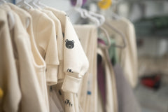 Natural colored baby clothes hanging on a rack. 