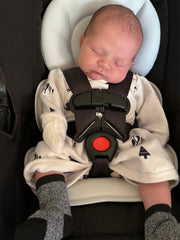 Newborn baby sleeping in car seat wearing a fleece newborn gown 