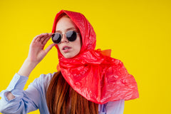 stylish young woman wearing sunglasses and  a red headscarf made from a plastic bag 