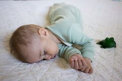 Sleeping baby wearing a mint green, long sleeve sleep sack 