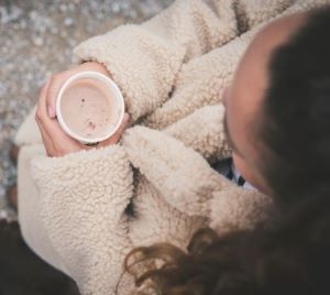 View from above of girl holding cup wearing a natural colored sherpa fleece jacket 