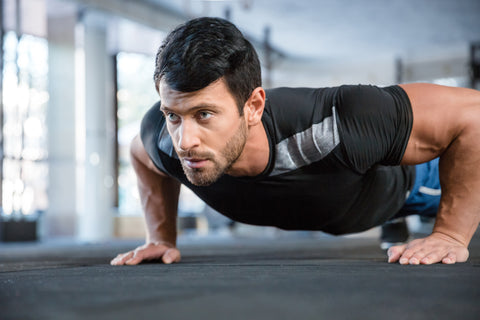 A man doing push ups in a gym.