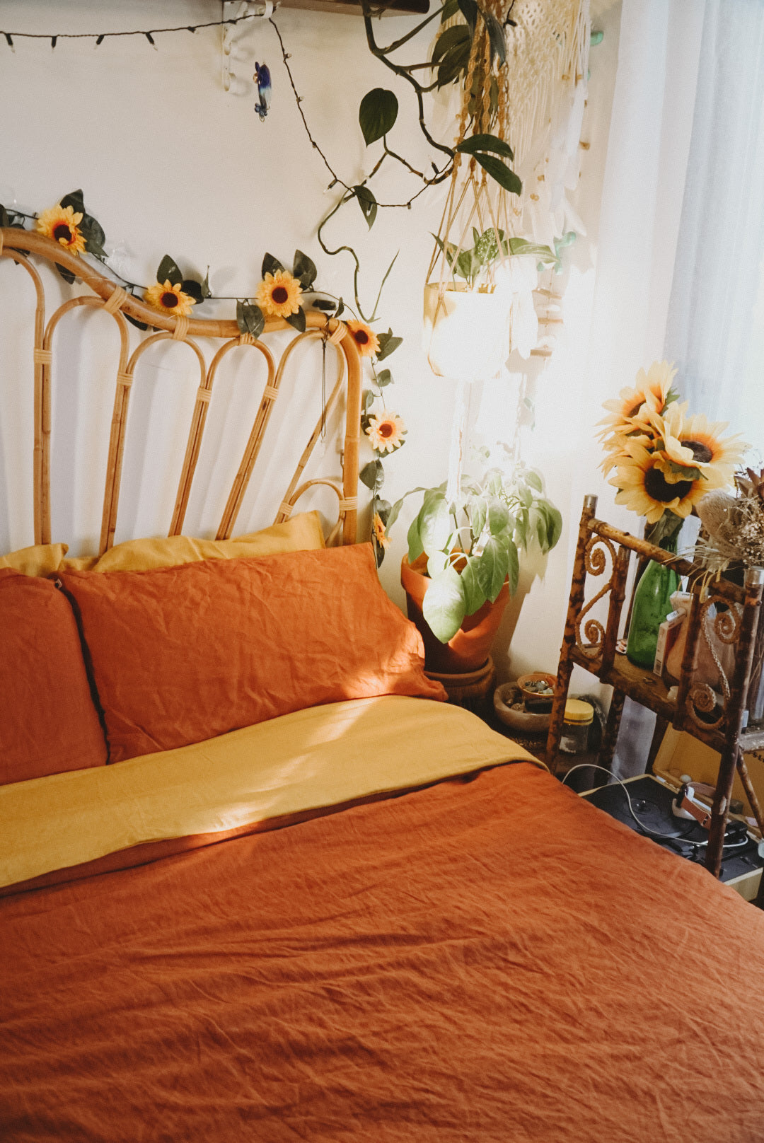 Eva's terracotta hemp linen sheets on a bed surrounded by thrifted items and sunflowers
