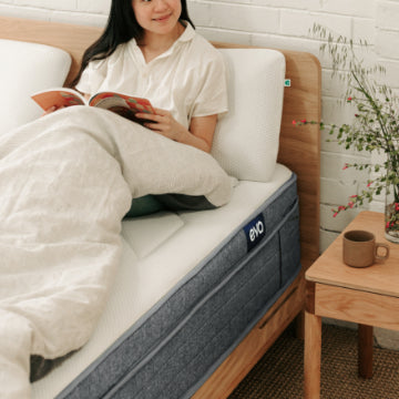Woman sitting up on bed reading magazine on Eva Bedroom products