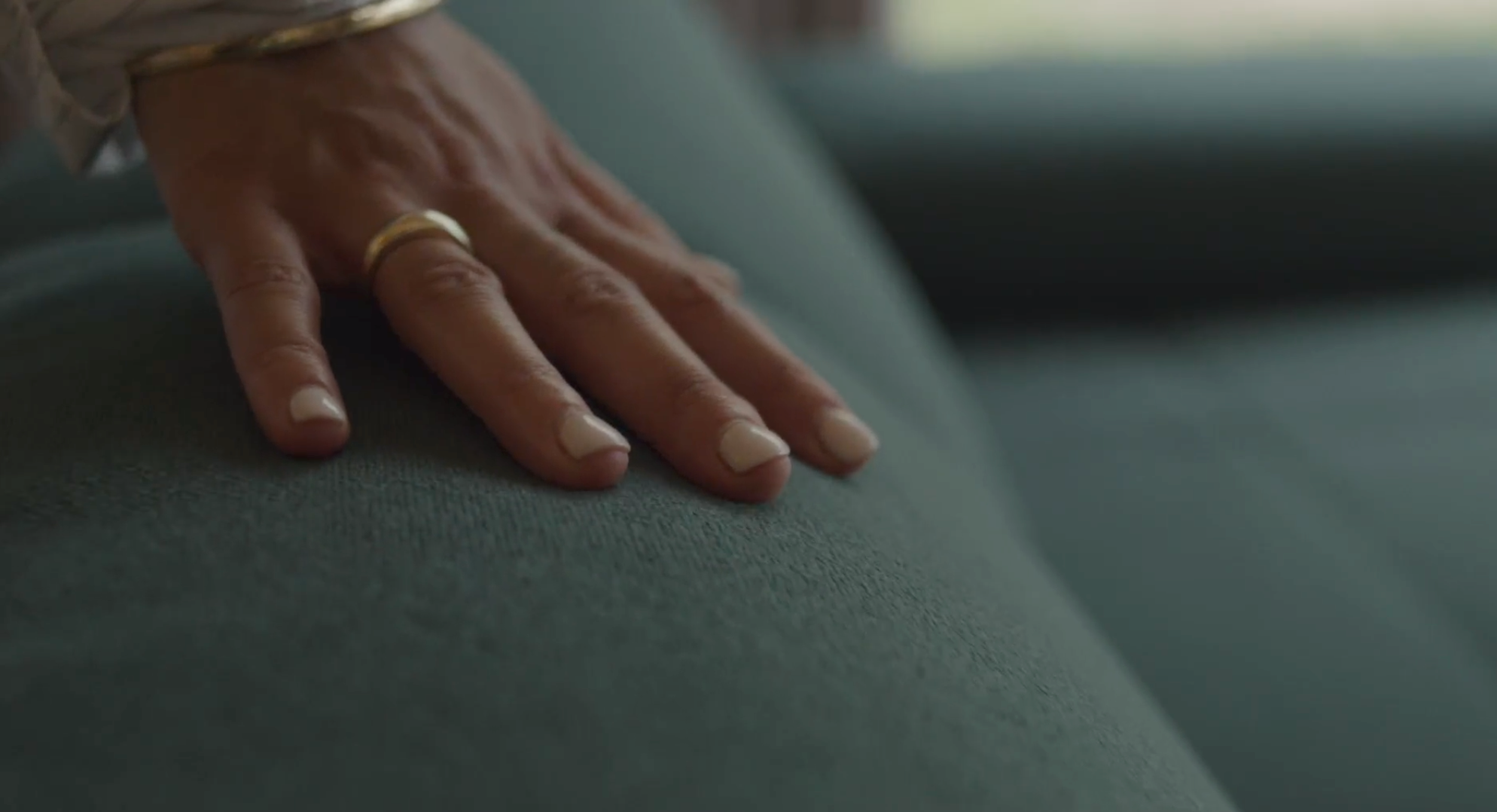 Close up of a woman's hand feeling the fabric of the Everyday Sofa in Moss green