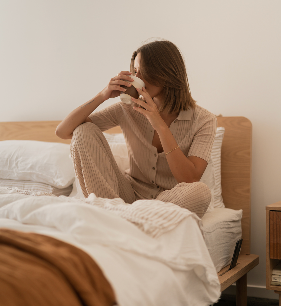 Woman sitting on an Eva bed drinking tea