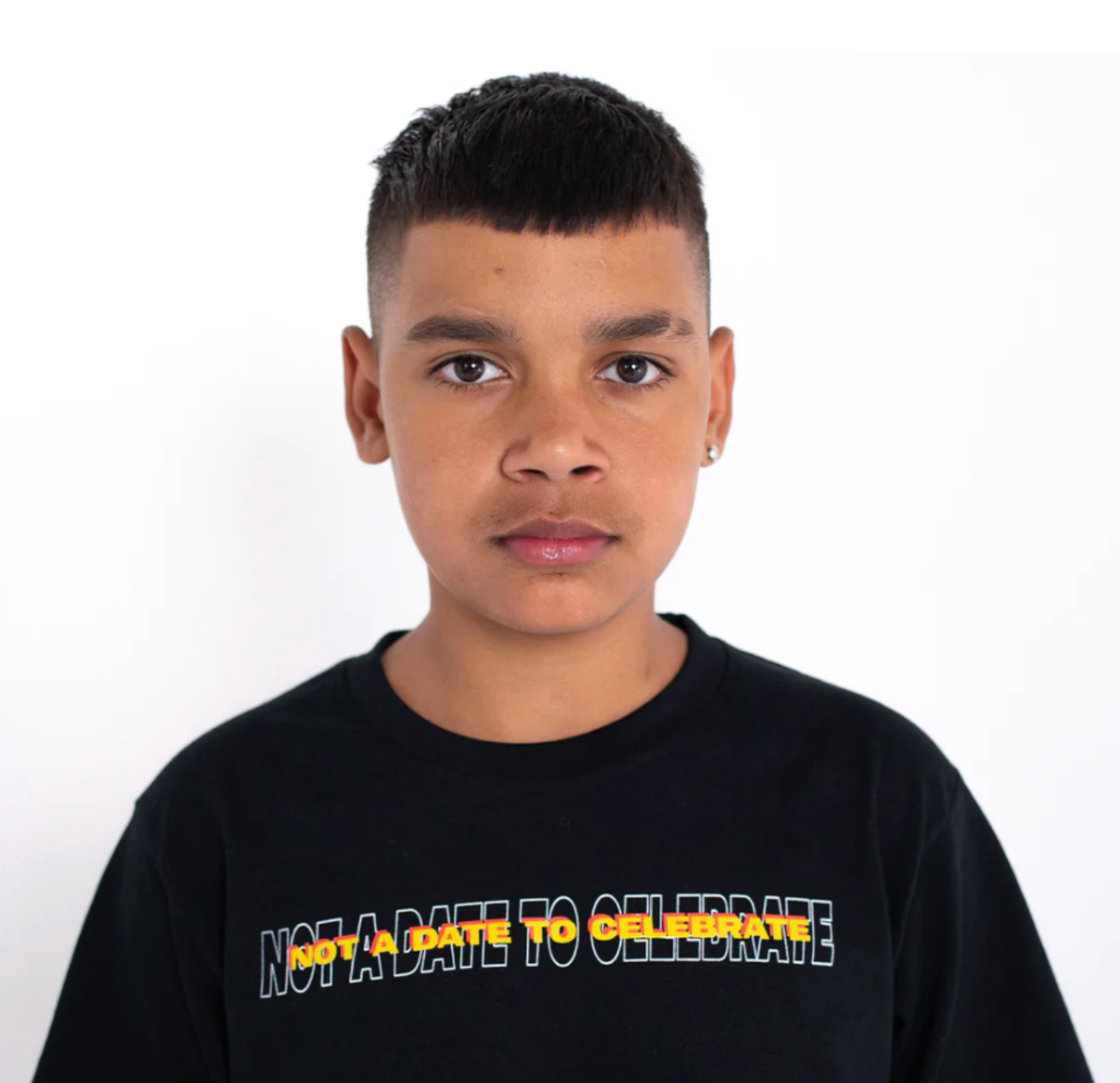 Boy faces the camera wearing a shirt that reads "Not a Date to Celebrate"