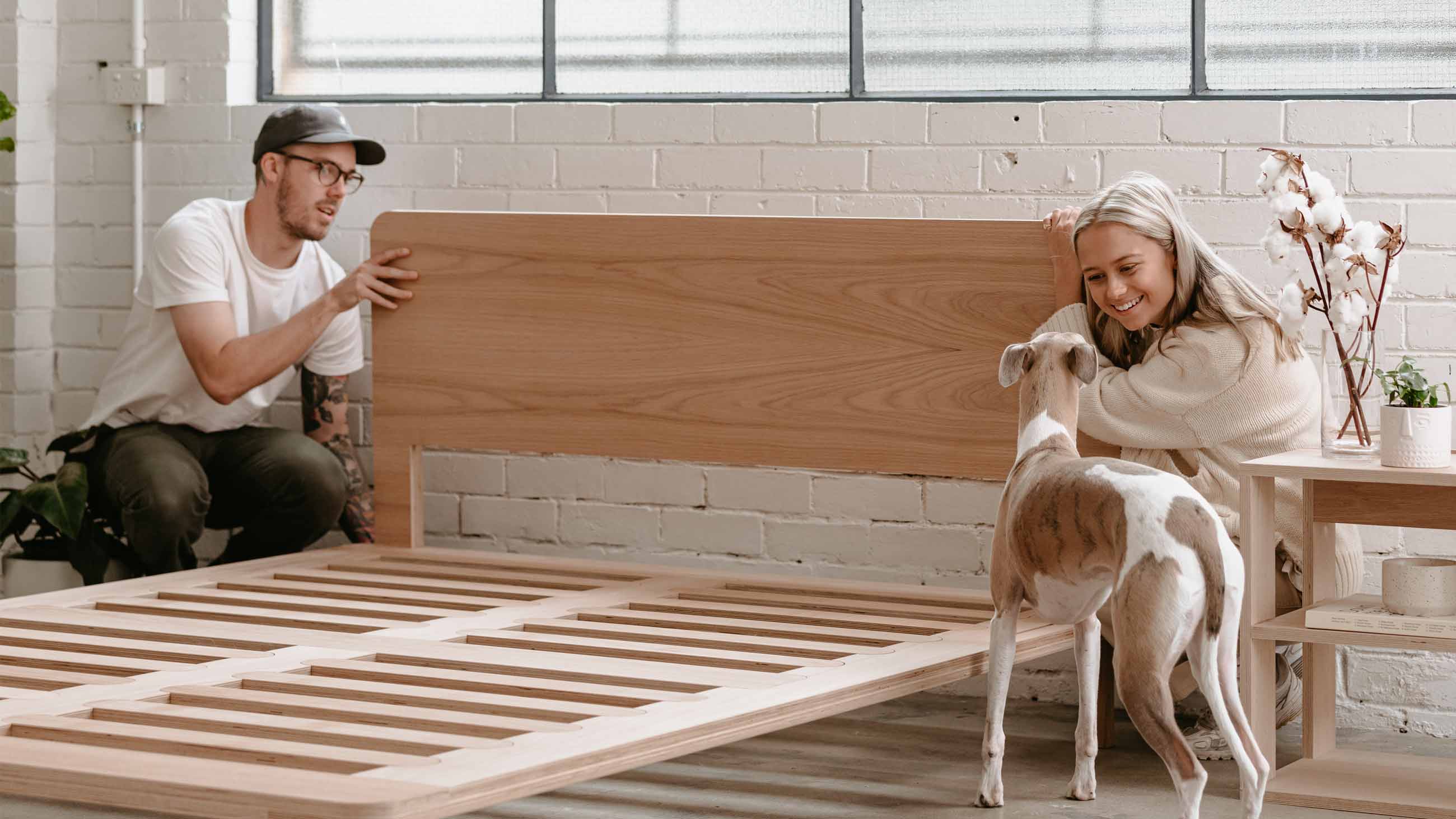 Man and woman assembling bed base with dog