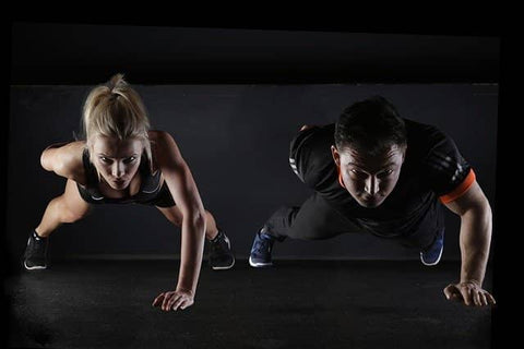 A man and a woman doing one-handed push-ups