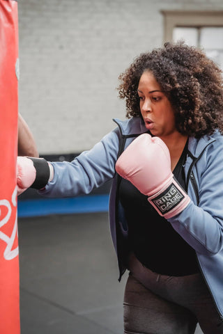 woman wearing pink boxing gloves while practicing
