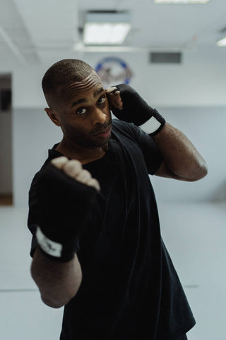 man in black boxing gloves practicing an uppercut facing the camera