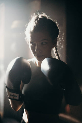 woman sparring with black boxing gloves