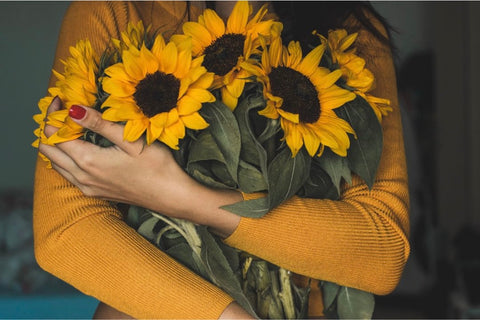 Woman in yellow shirt holding bouquet of sunflowers