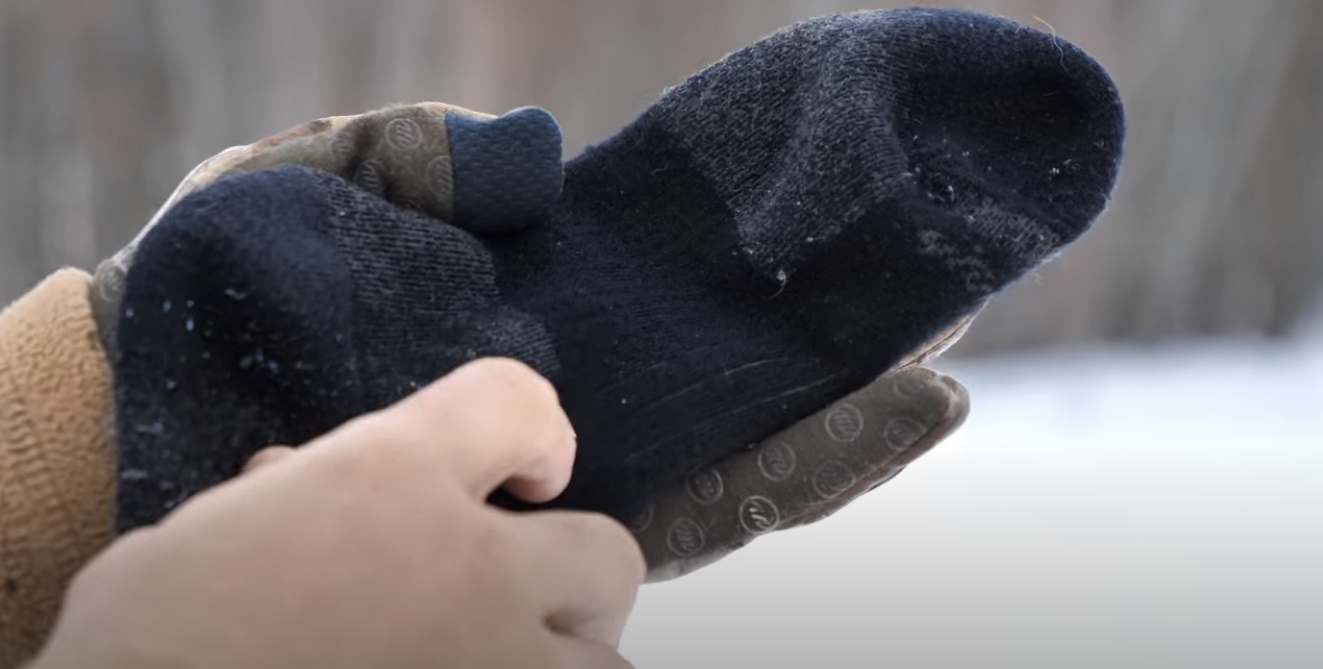 Person holding Darn-tough socks in a winter setting