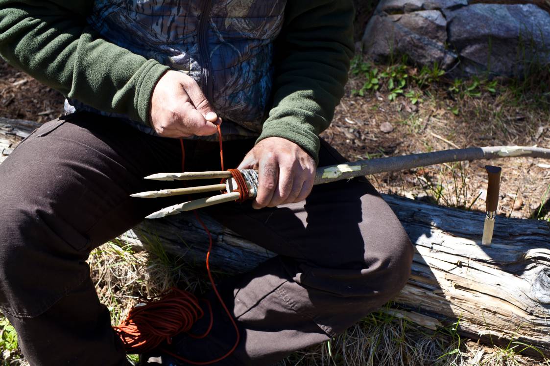 Man making a fishing spear with a utility knife