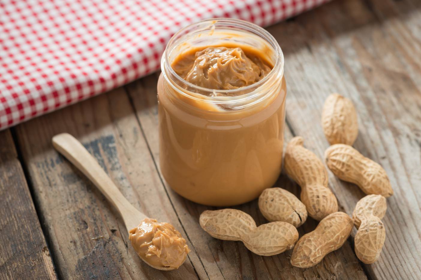 Peanut butter jar with peanuts resting beside