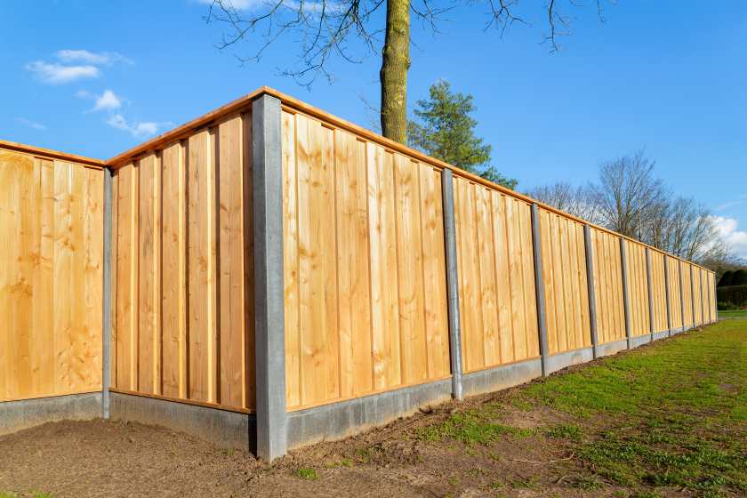 Tall fence to keep intruders out, surrounding a home during the summer.