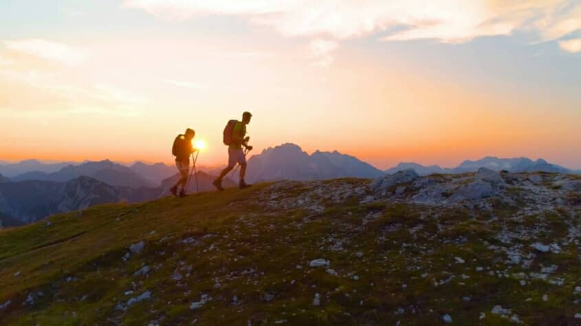 Two people trekking in the sunset