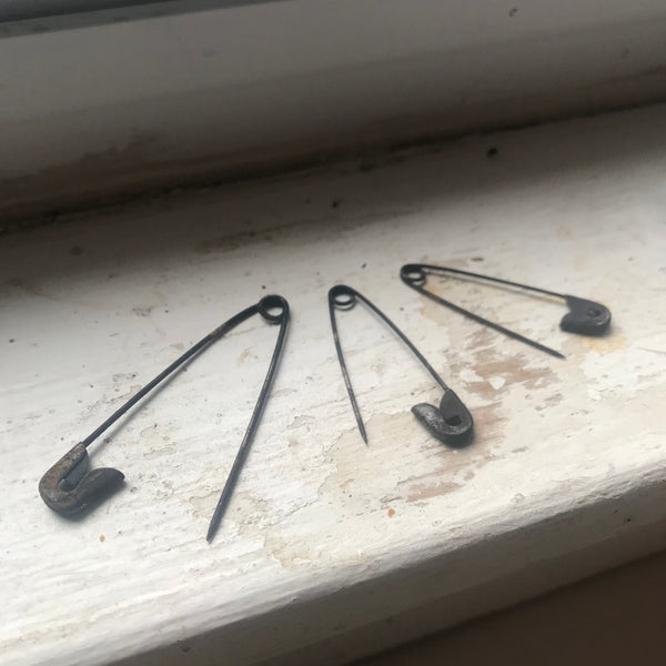 Old dark safety pins on windowsill