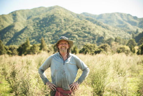 7 Ways To Be A More Mindful Consumer - ManukaRx New Zealand farmer smiling in a field of mānuka plants.