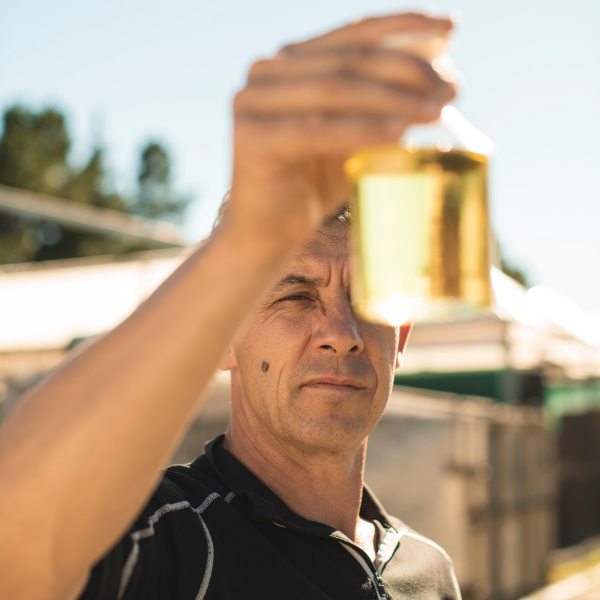 Hold the Prescription: 5 Natural Antibiotic Alternatives image showing a male holding a bottle of East Cape Manuka essential oil at a distillery.