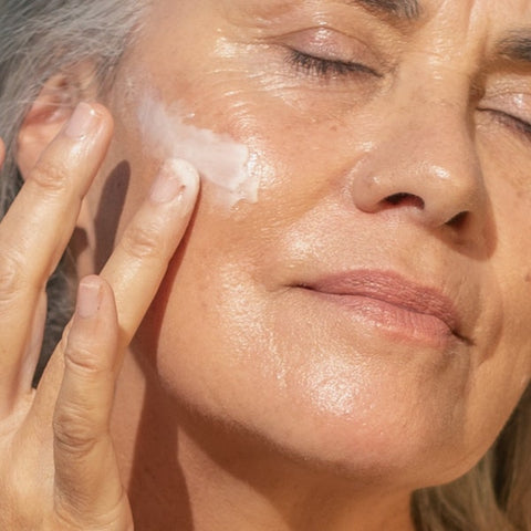 A woman with beautifully radiant skin, showcasing a healthy and luminous complexion, holding a cream that enhances the skin's natural glow, exemplifying the transformative effects of the product on her skin's appearance