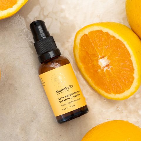 Vitamin C Serum bottle immersed in crystal-clear water, accompanied by vibrant orange slices.