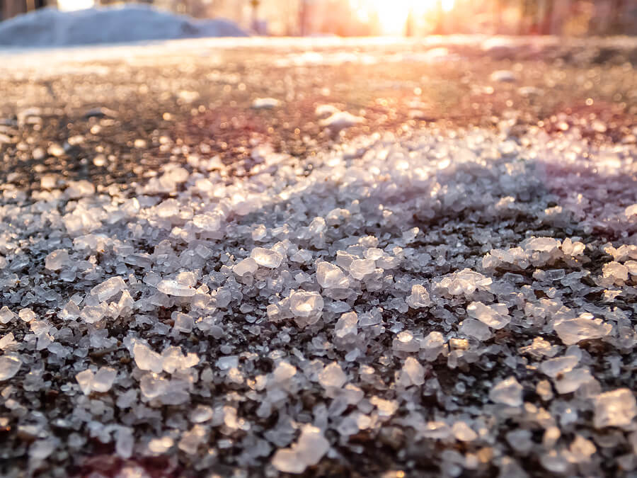 Salt grains on icy sidewalk surface in the winter. 