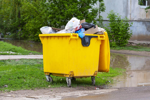 A yellow wheelie bin full of waste