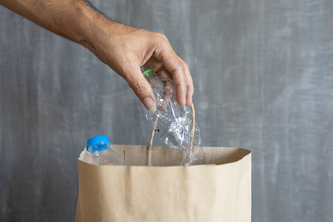 A brown paper bag being used as a bin for plastic bottles