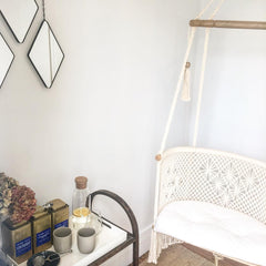 Hanging chair made in cotton with macrame technique. cream color pattern and cream cushion.