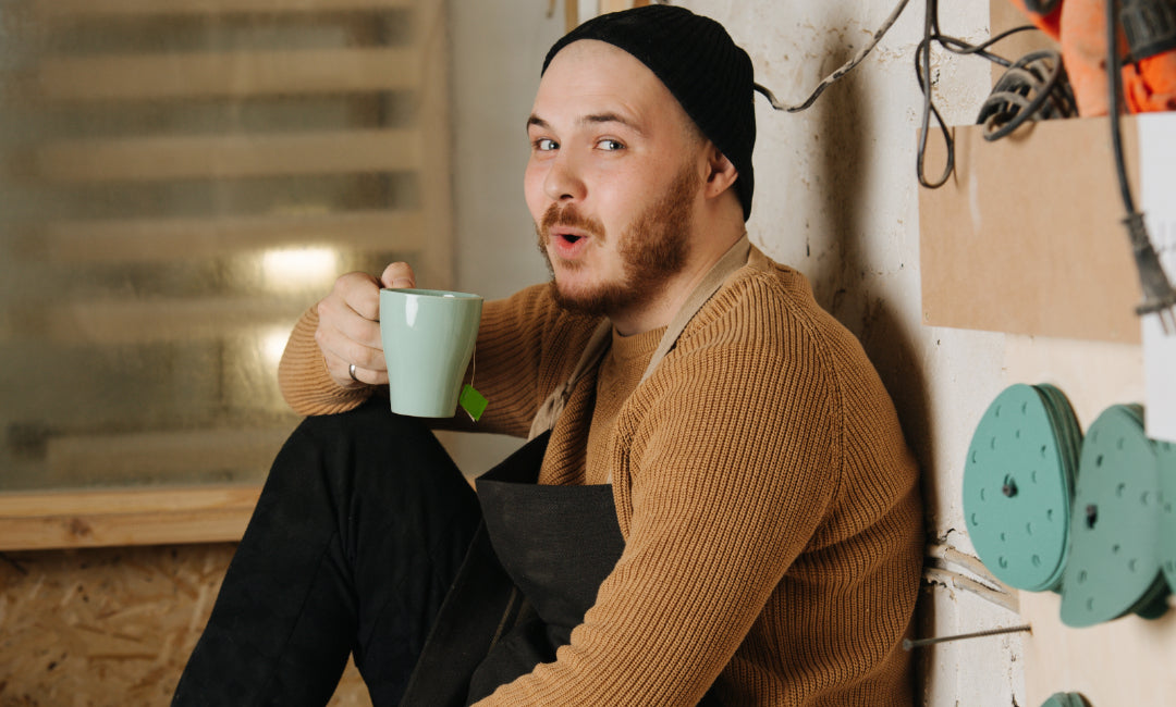 Funny carpenter in a watch cap drinking tea from a mug