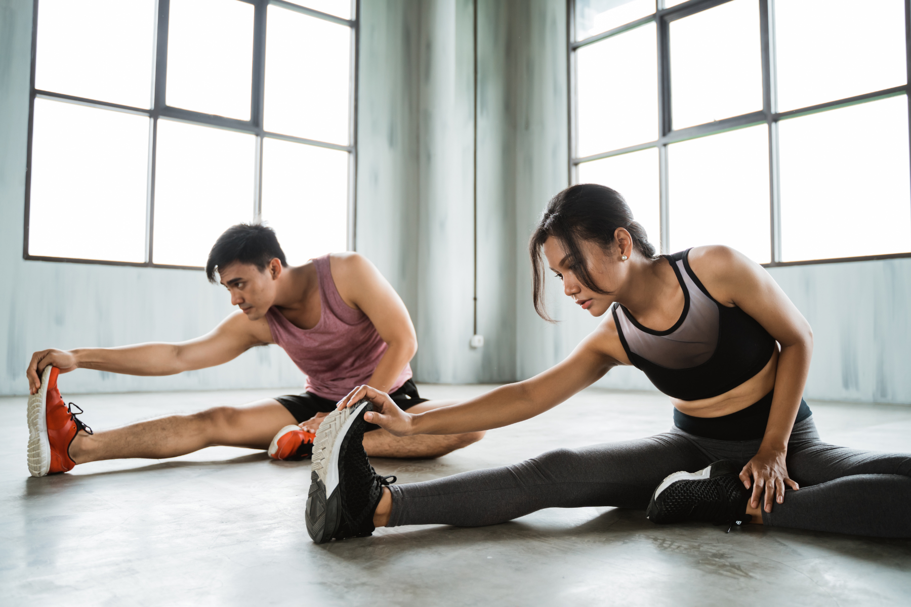 man and woman doing seated hamstring stretch