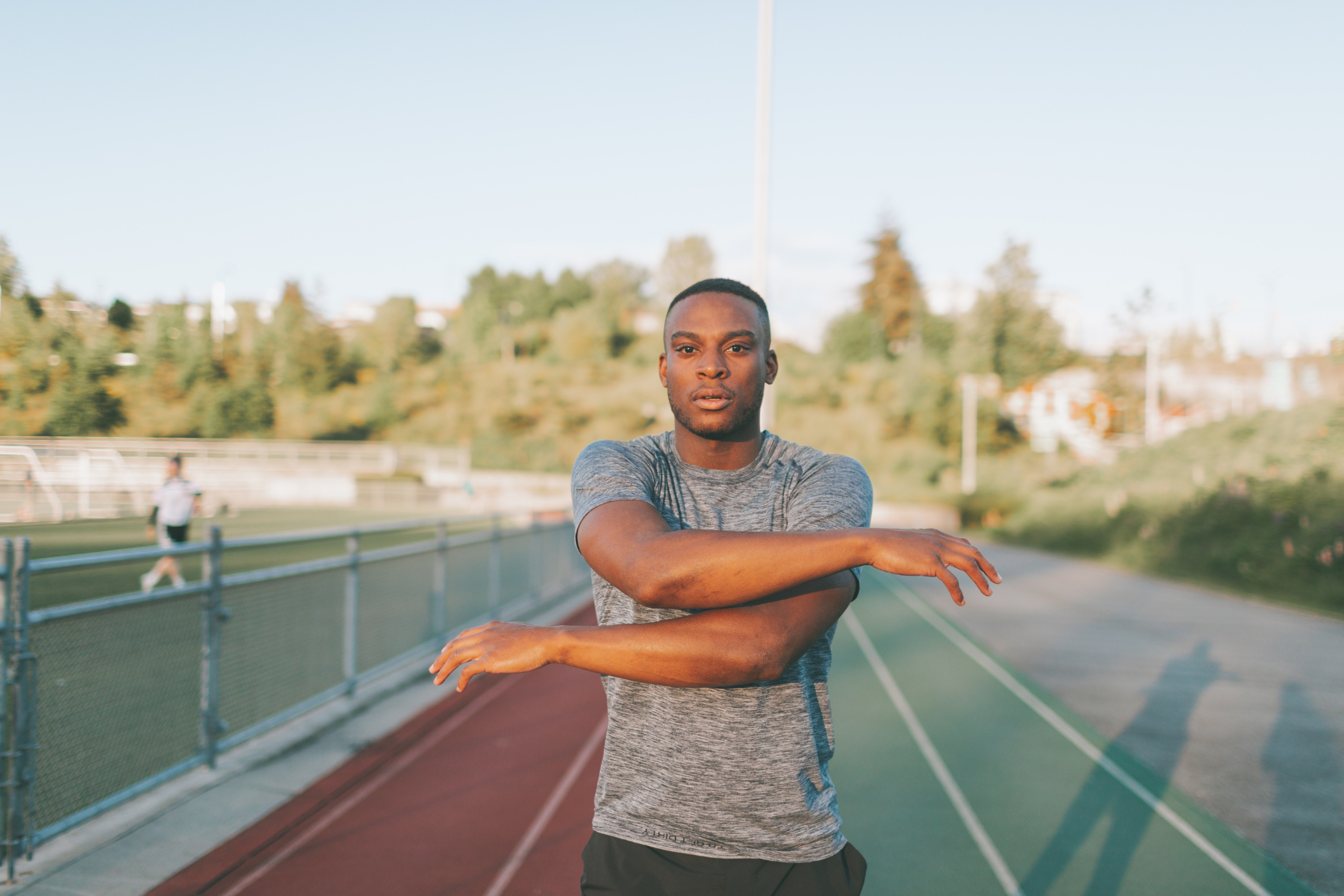 man on running track crossing arms in front of chest