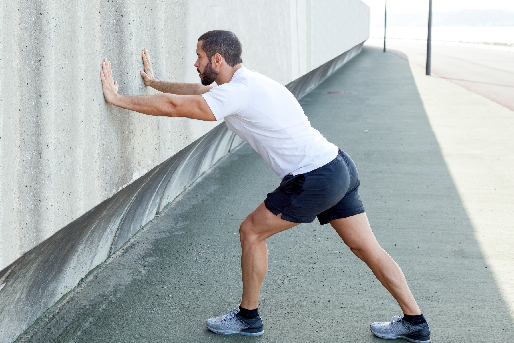 Man with hands on wall stretching calves