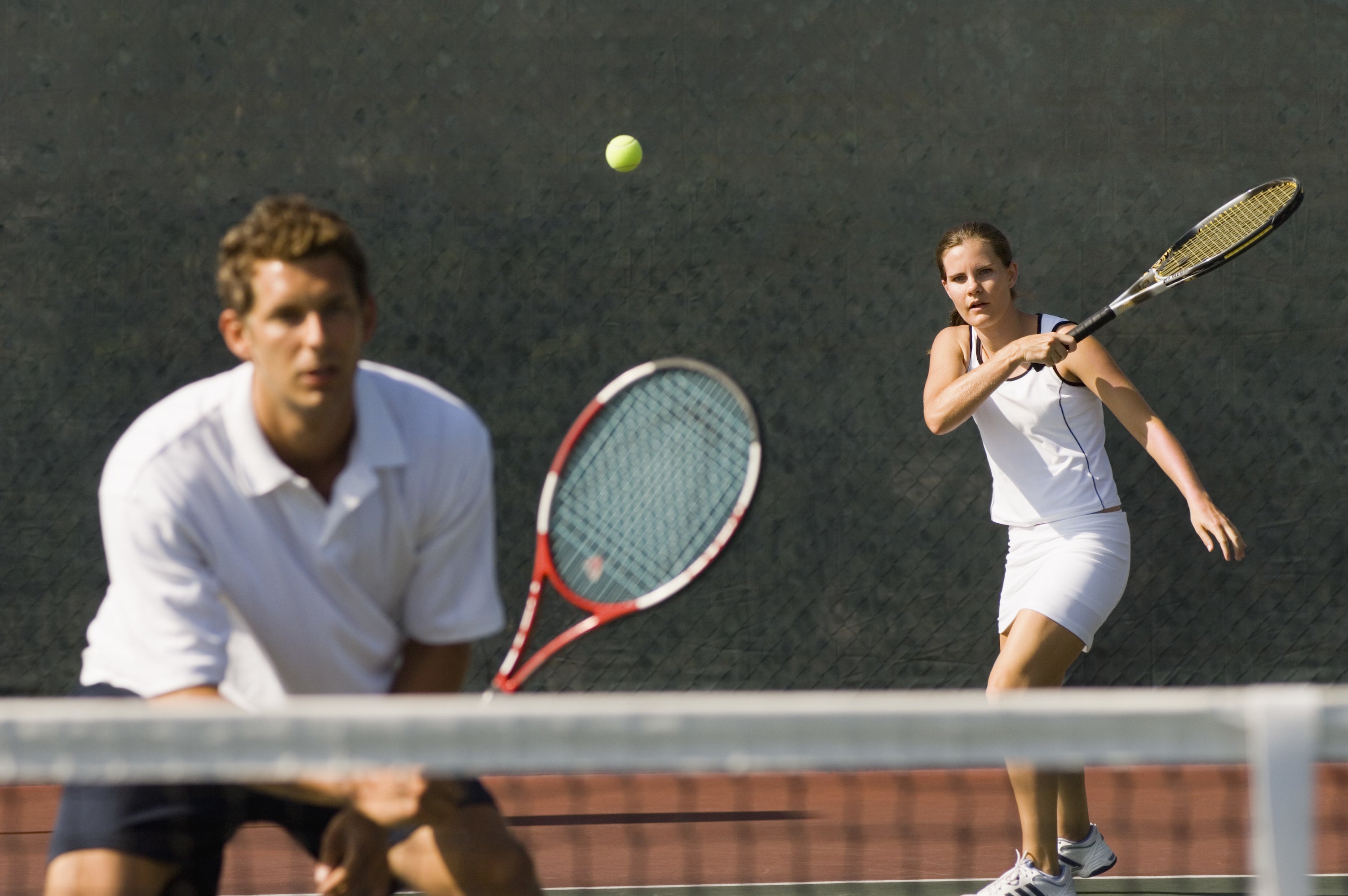 Man and woman playing doubles tennis