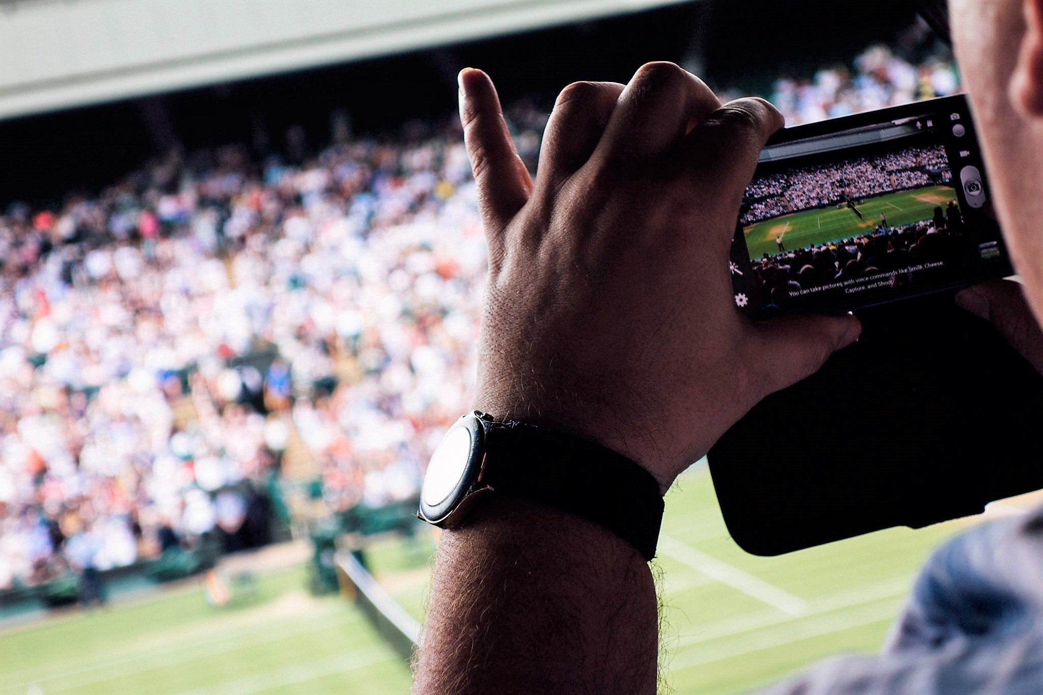 Tennis spectator recording an image