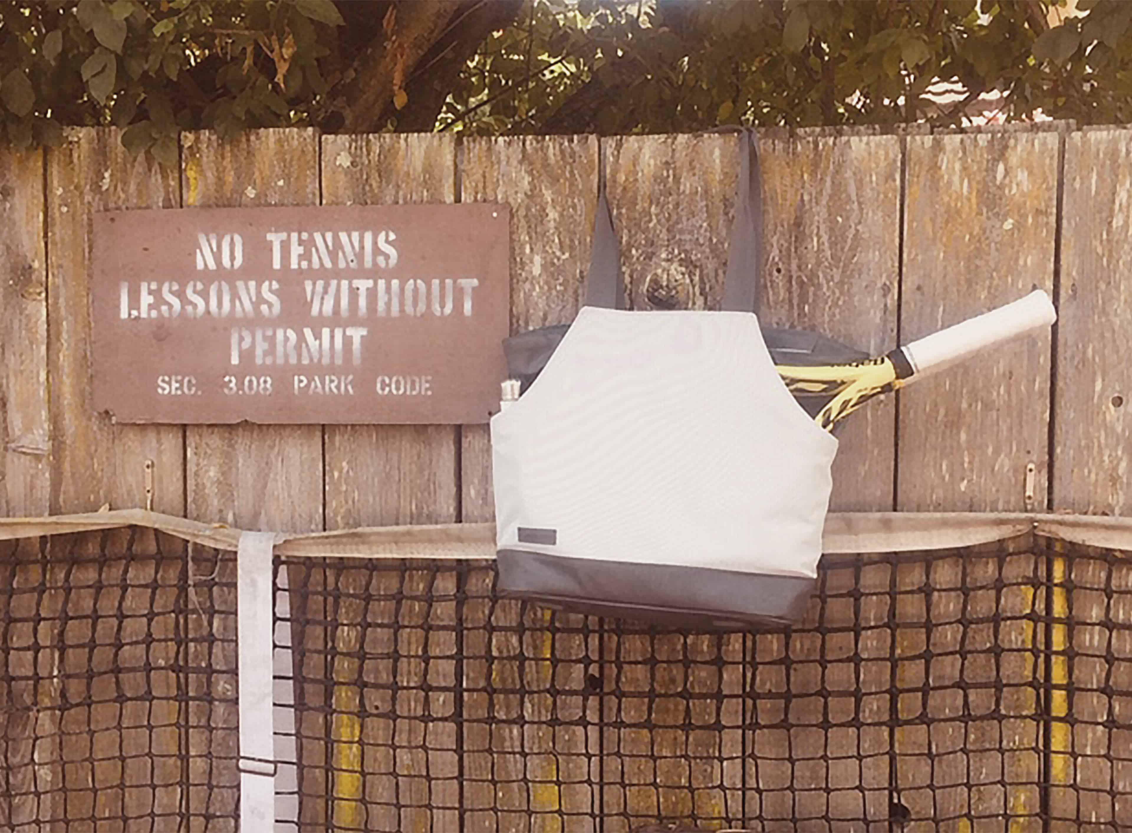 Doubletake tennis bag against wooden fence.