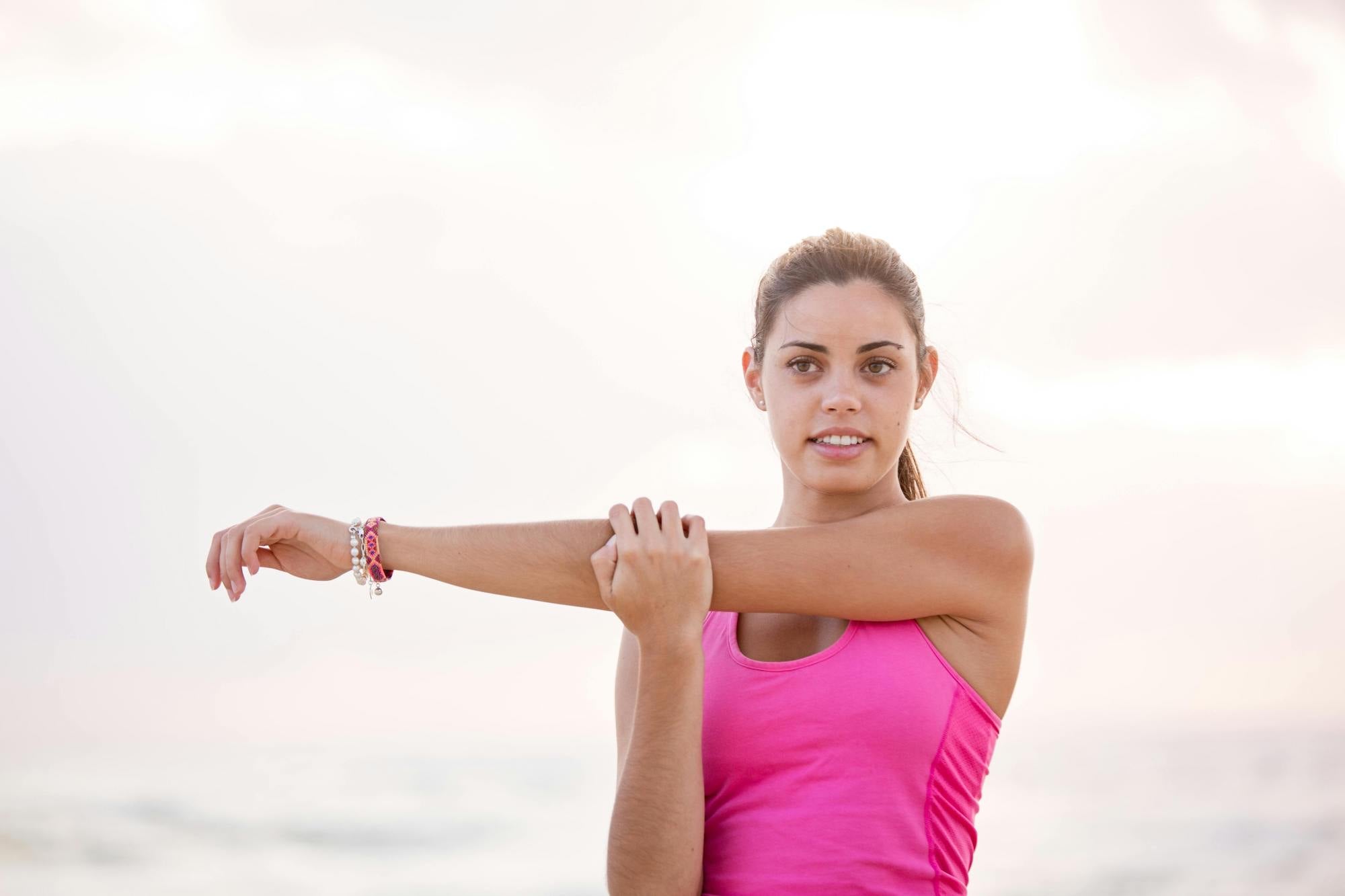 woman stretching left arm across chest