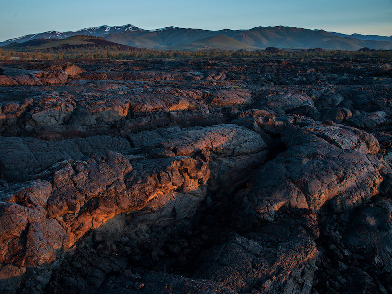 Weird rock formations beneath blue sky and mountains in distance